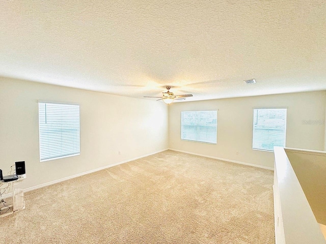 empty room featuring baseboards, visible vents, a textured ceiling, and light colored carpet