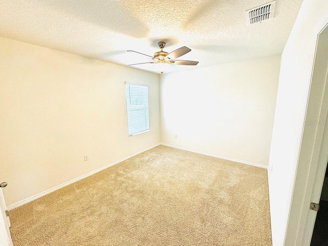 carpeted empty room with baseboards, a textured ceiling, visible vents, and a ceiling fan