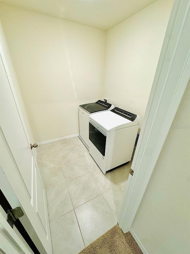 washroom featuring laundry area, independent washer and dryer, light tile patterned flooring, and baseboards