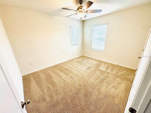 unfurnished room featuring light carpet, a textured ceiling, a ceiling fan, and baseboards