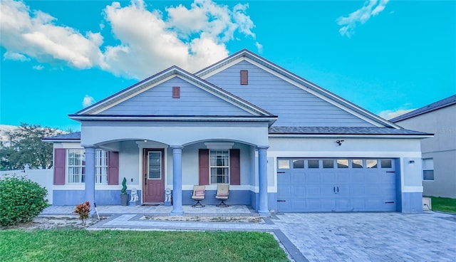 view of front of house featuring decorative driveway, roof with shingles, stucco siding, covered porch, and an attached garage