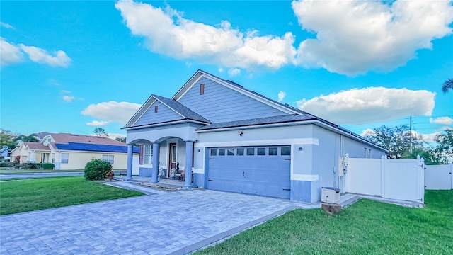 view of front of house with a garage, covered porch, fence, decorative driveway, and a front lawn