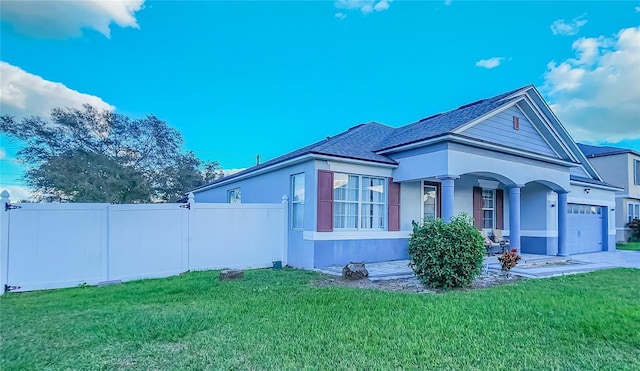 view of side of home featuring an attached garage, fence, concrete driveway, a yard, and stucco siding