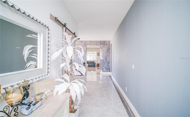 hallway with a barn door and baseboards