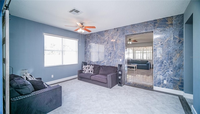 living room featuring a ceiling fan, visible vents, baseboards, and tile patterned floors