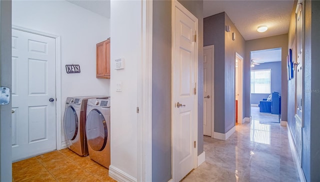 laundry area with cabinet space, baseboards, separate washer and dryer, and a textured ceiling