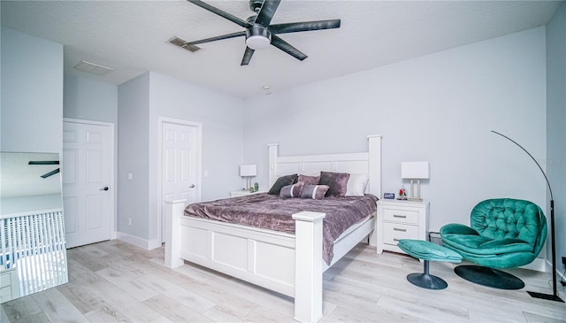 bedroom featuring a textured ceiling, a ceiling fan, visible vents, and light wood-style floors