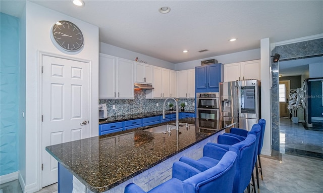 kitchen featuring appliances with stainless steel finishes, white cabinetry, a sink, and a breakfast bar area