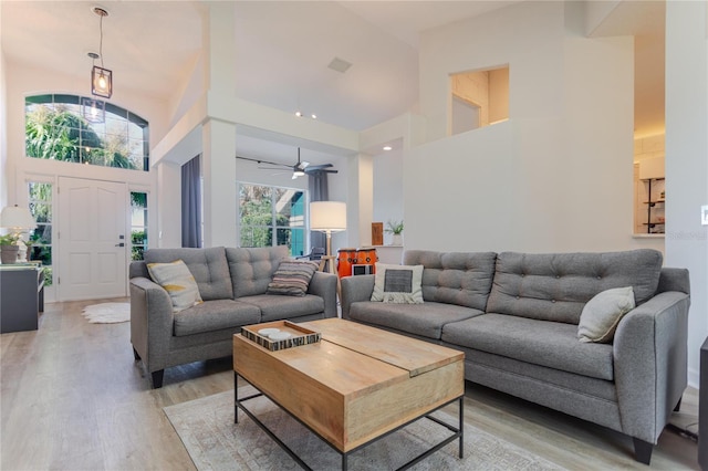 living area with a high ceiling, visible vents, and wood finished floors