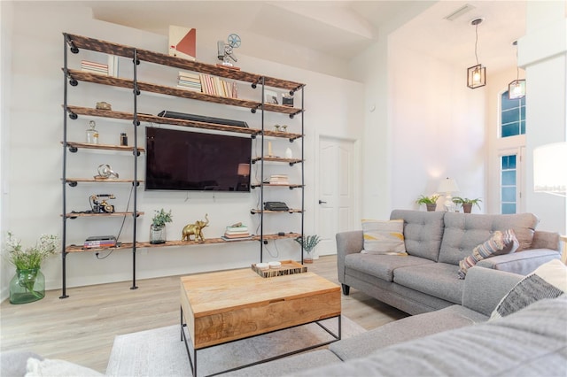 living area featuring a towering ceiling and light wood-style flooring