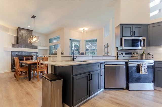 kitchen with a sink, light countertops, appliances with stainless steel finishes, backsplash, and a wealth of natural light