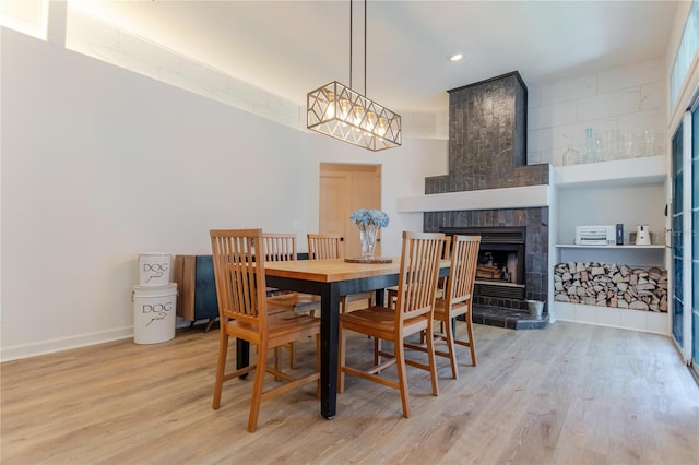 dining room with recessed lighting, a fireplace, light wood-style flooring, and baseboards