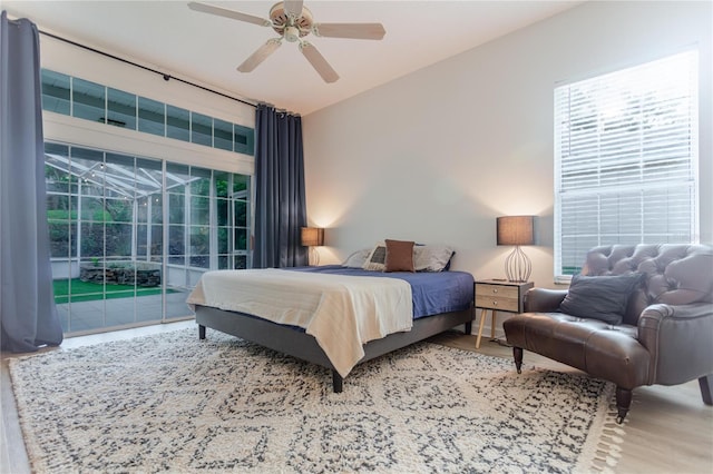 bedroom featuring a ceiling fan, wood finished floors, a sunroom, and access to exterior