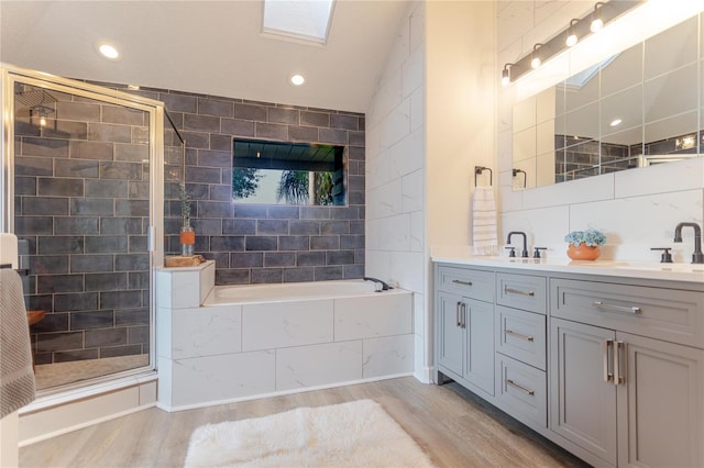 bathroom with a garden tub, tile walls, a sink, and wood finished floors