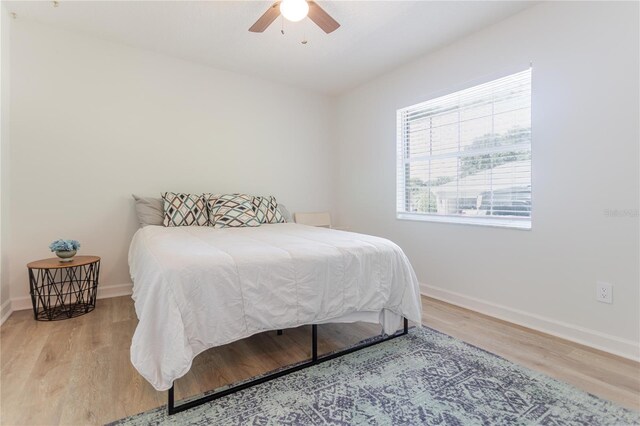 bedroom with light wood finished floors, ceiling fan, and baseboards