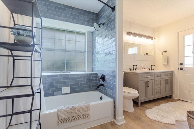 full bath featuring toilet, wood finished floors, backsplash, double vanity, and washtub / shower combination