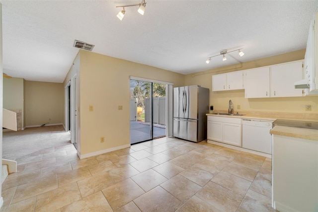 kitchen with freestanding refrigerator, white dishwasher, light countertops, white cabinetry, and a sink