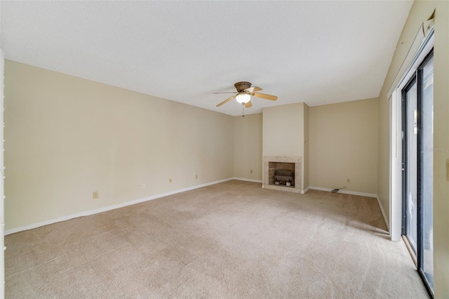 unfurnished living room with a ceiling fan, light colored carpet, a fireplace, and baseboards