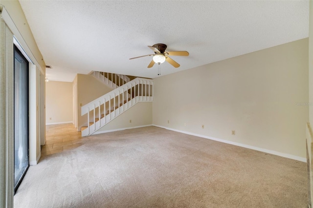 unfurnished room with stairs, a textured ceiling, baseboards, and light colored carpet