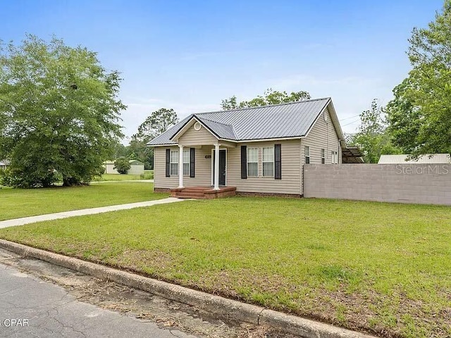 single story home featuring a front yard, metal roof, and fence