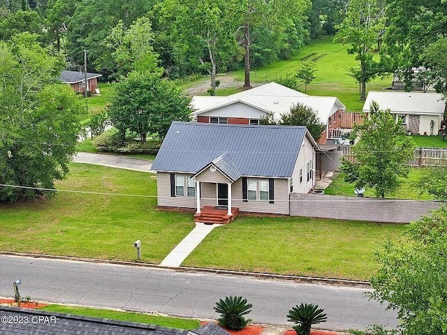 view of front of house featuring fence, metal roof, and a front yard