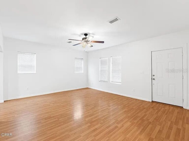 spare room with ceiling fan, light wood-type flooring, visible vents, and baseboards