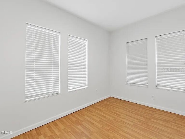 empty room with light wood-style flooring and baseboards