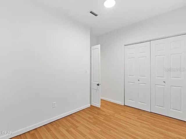 unfurnished bedroom with visible vents, a closet, light wood-style flooring, and baseboards