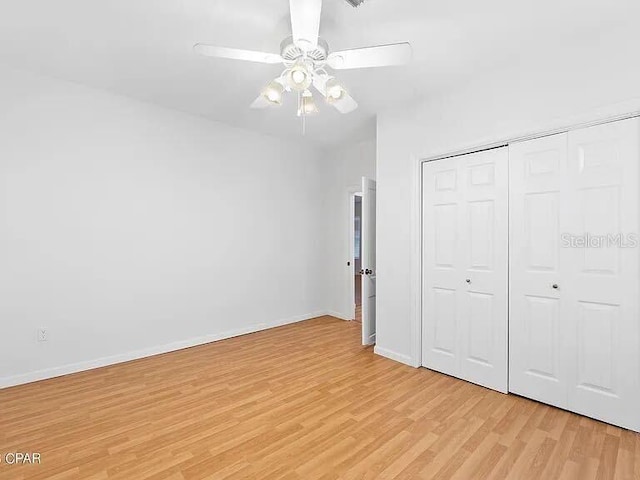 unfurnished bedroom featuring a closet, light wood-type flooring, a ceiling fan, and baseboards