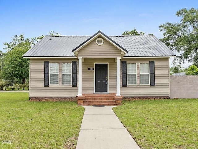 bungalow-style home with metal roof and a front yard