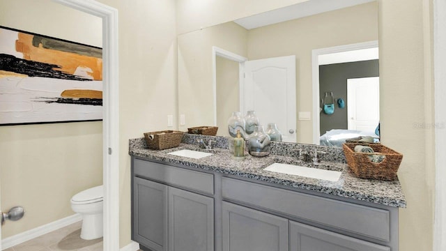 ensuite bathroom featuring toilet, ensuite bath, double vanity, and a sink