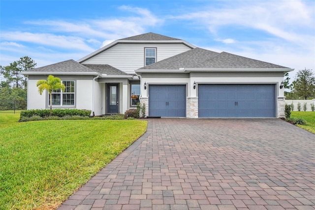 view of front of home featuring an attached garage, a shingled roof, decorative driveway, and a front yard