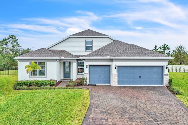 traditional-style house featuring an attached garage, a shingled roof, a front lawn, and decorative driveway