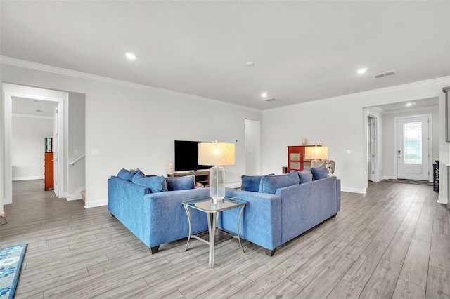 living room with light wood-style floors, baseboards, visible vents, and ornamental molding