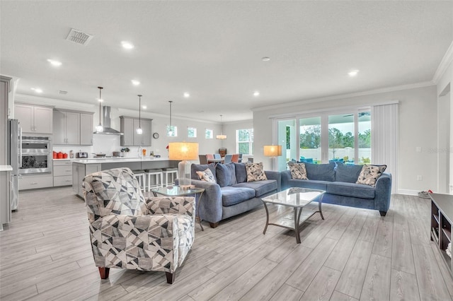 living area with ornamental molding, recessed lighting, visible vents, and light wood-style floors