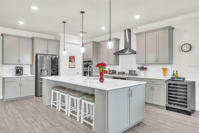 kitchen featuring beverage cooler, stainless steel appliances, wall chimney range hood, and gray cabinets