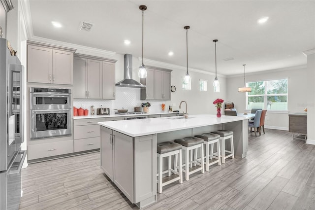 kitchen featuring stainless steel appliances, gray cabinets, light countertops, visible vents, and wall chimney exhaust hood