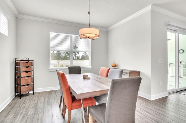 dining area with light wood-type flooring, crown molding, and baseboards