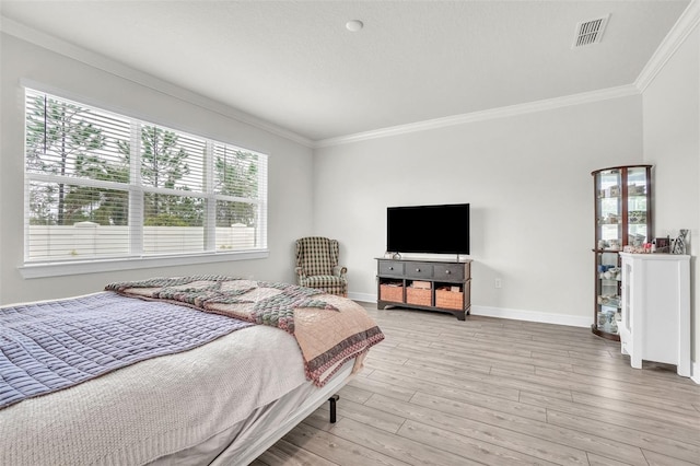 bedroom with light wood-type flooring, baseboards, visible vents, and ornamental molding