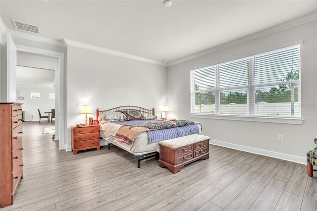 bedroom with ornamental molding, baseboards, visible vents, and light wood finished floors