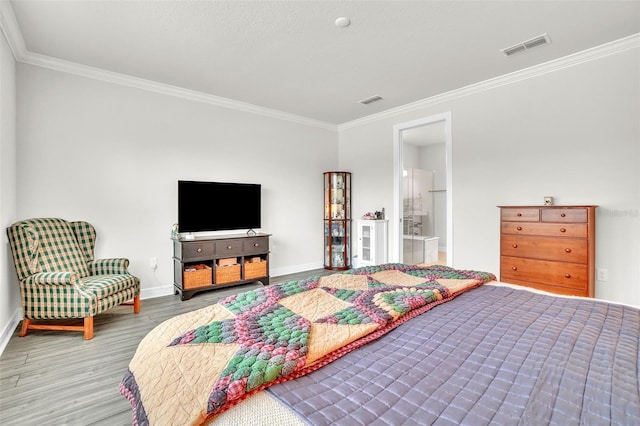 bedroom with ensuite bathroom, wood finished floors, visible vents, baseboards, and ornamental molding