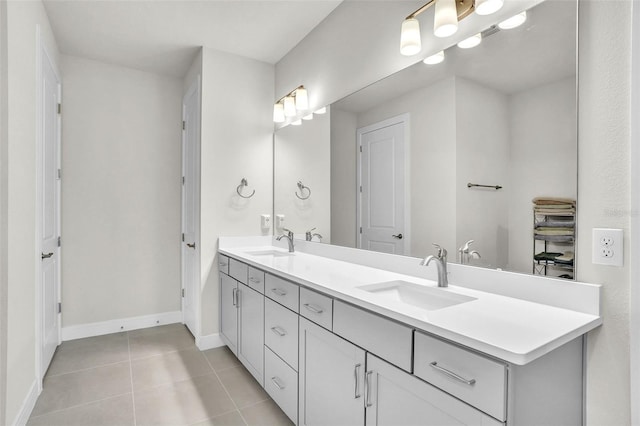 full bath with baseboards, double vanity, a sink, and tile patterned floors