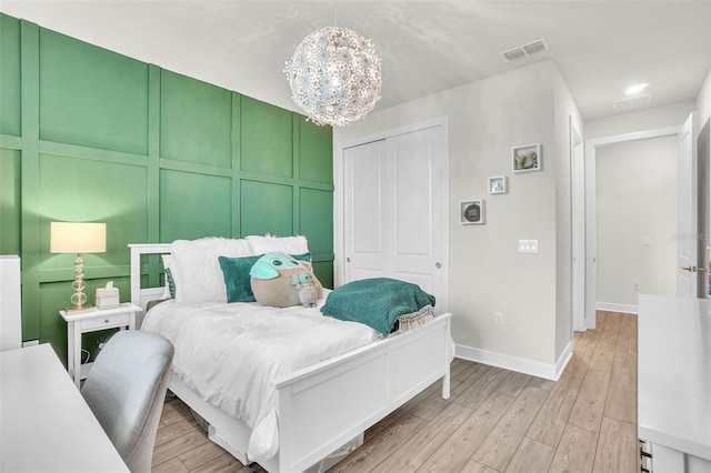 bedroom featuring a notable chandelier, a closet, visible vents, light wood-type flooring, and baseboards