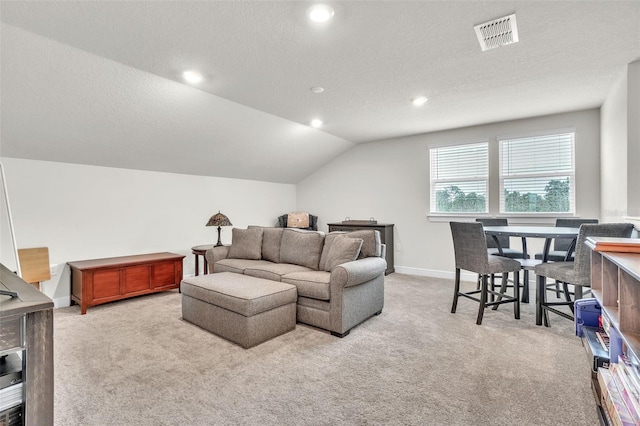 living room with lofted ceiling, visible vents, light carpet, and a textured ceiling