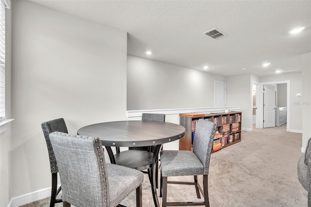 dining room featuring recessed lighting, light colored carpet, visible vents, a textured ceiling, and baseboards