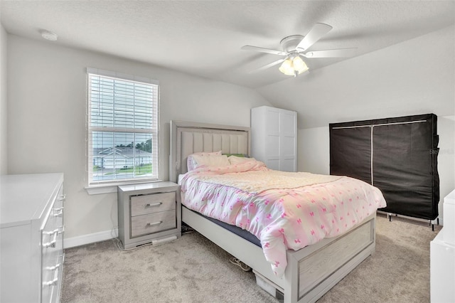 bedroom with a textured ceiling, lofted ceiling, light carpet, a ceiling fan, and baseboards