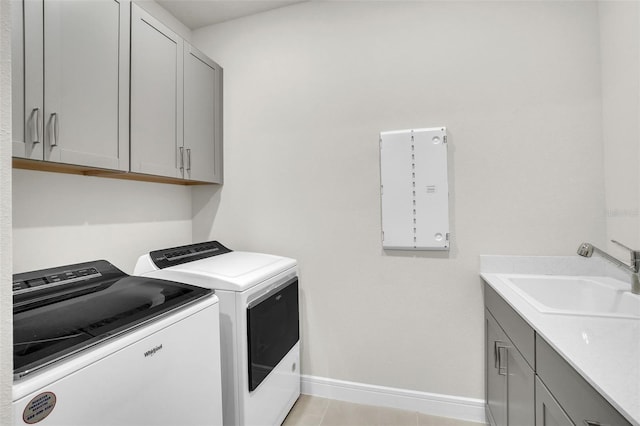 clothes washing area featuring cabinet space, baseboards, washer and clothes dryer, and a sink