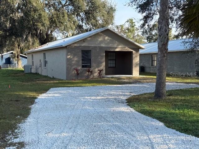 single story home with driveway, brick siding, a front yard, and cooling unit