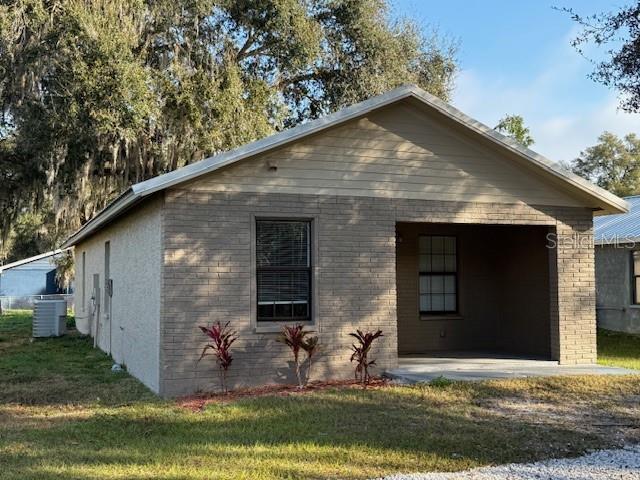 exterior space with central AC, a yard, and brick siding