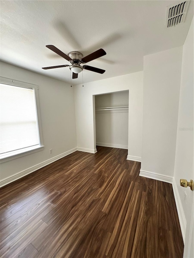 unfurnished bedroom with dark wood-style floors, a closet, visible vents, and baseboards